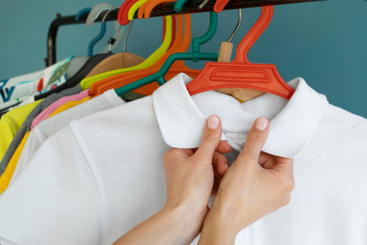 uniform hung up on colourful hangers, with hands buttoning up a white polo shirt